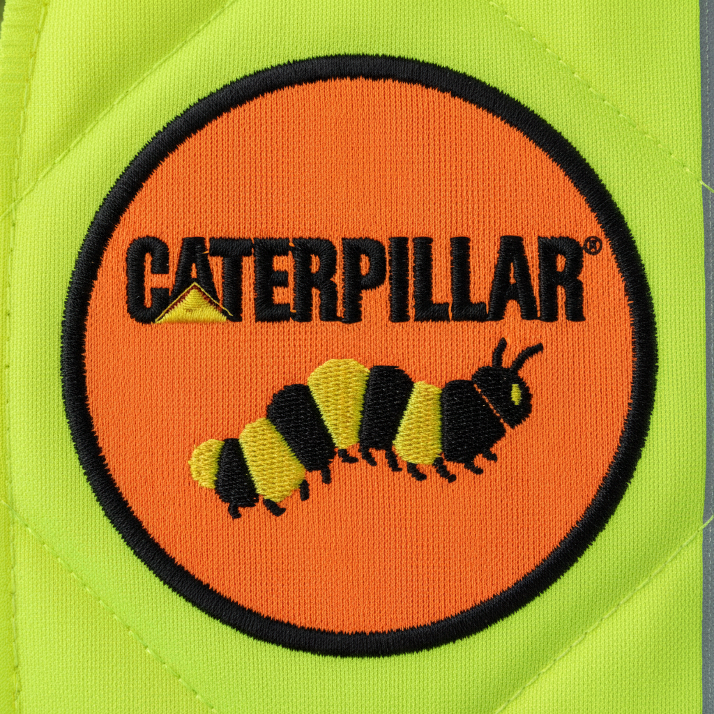 Macro embroidery detail of Caterpillar logo on hi-vis safety workwear showing raised 3D puff thread texture