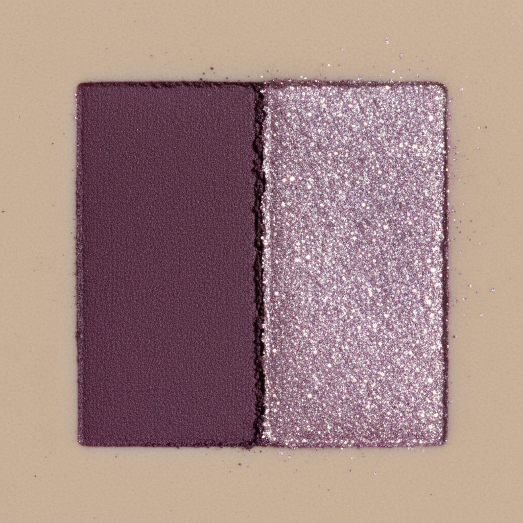 Close-up texture swatch of matte plum and shimmer lilac eyeshadow pigments