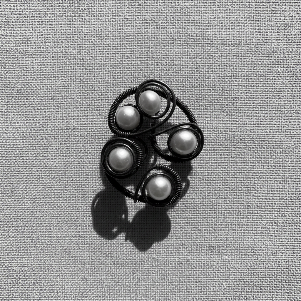 Silver petal-shaped stud earrings with pearl center on cream textured background, bright minimalist editorial photography